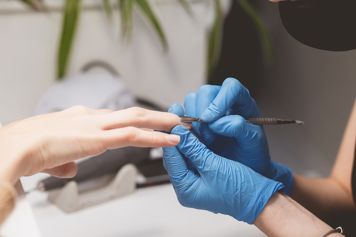 Manicurist cuts cuticle to prepare nails for painting. Manicure procedure